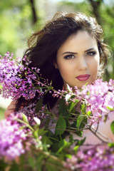 Fototapeta premium Young brunette woman with lilac flowers, Outdoors portrait