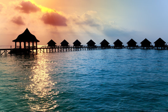 Houses On Piles On Water At The Time Sunset.