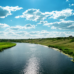 river with reflections and blue cloudy sky over it