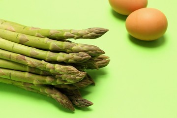Asparagus and eggs on green background