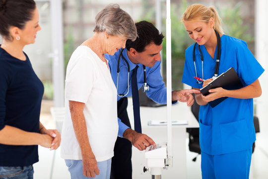 medical doctor monitoring senior patient's weight
