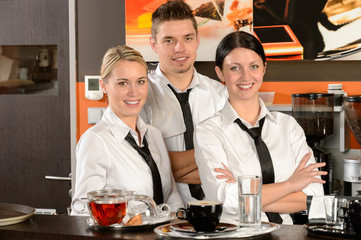 Three server posing in uniform in cafe