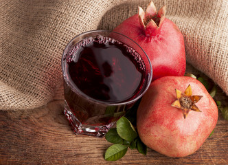 Garnet juice in a glass and pomegranate on wooden boards