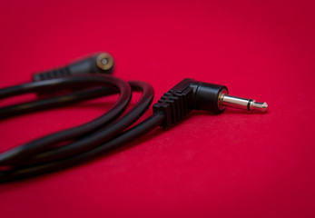 a coiled up 1/8 stereo jack cable on a red textured background