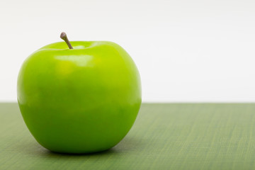 a left justified plastic green apple on patterned ground