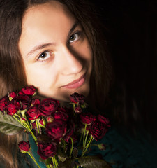Portrait of the young girl holding red flowers
