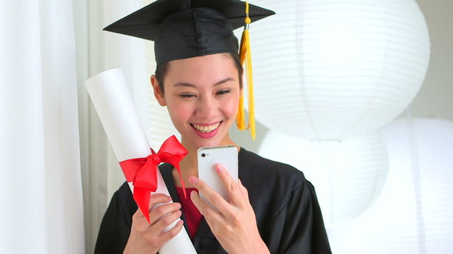 Mixed Race Asian graduate taking picture with smart phone