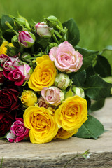 Fabulous bouquet of colorful roses on wooden tray in fresh sprin