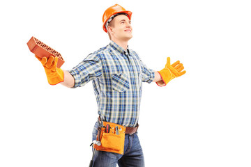 Happy manual worker holding a brick and spreading arms