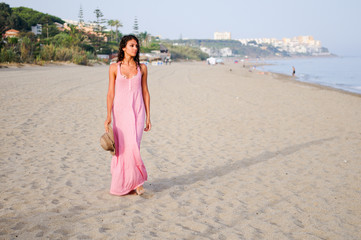 Fototapeta na wymiar Beautiful woman with long pink dress on a tropical beach