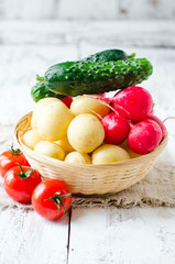 Fresh young potatoes , radish and cucumbers in a basket