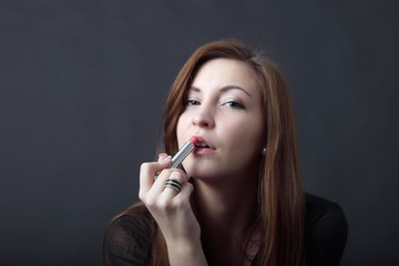 beautiful young woman applying lipstick