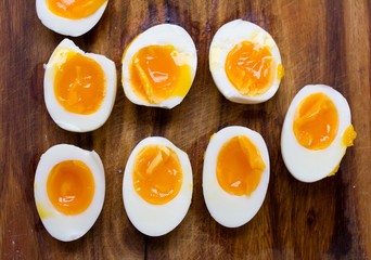 Hard boiled eggs, sliced in halves on wooden background