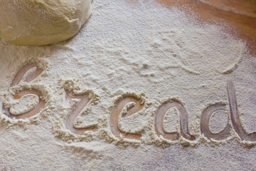 Background with word bread in scattering flour on wooden table