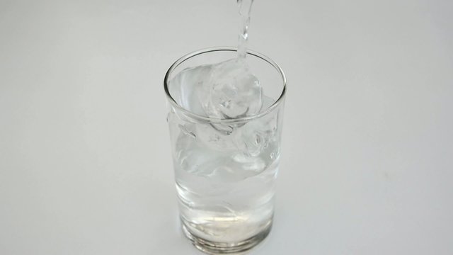Pouring drinking water into a glass in white background