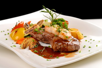 Delicious juicy barbequed steak and prawns with grilled tomato