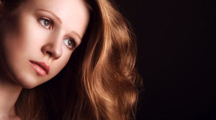 Naklejka premium sad, melancholy girl with long red hair on a dark background