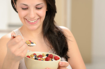 Joyful woman eating healthy cereal for breakfast