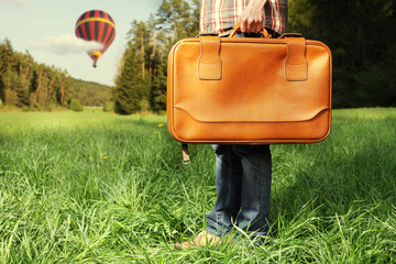 Man with travel bag standing on green lawn