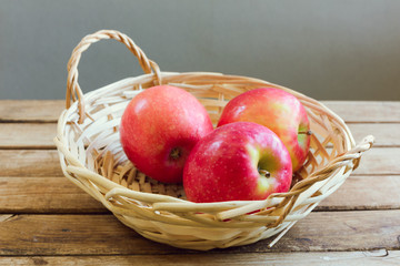 Red apples in basket on wooden deck table