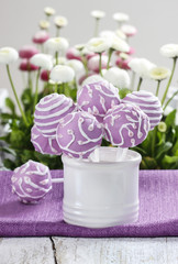 Lilac cake pops in white ceramic jar. White and pink daisies