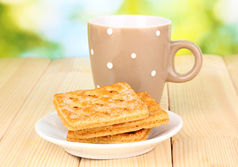 Cup of tea and cookies on wooden table on bright background