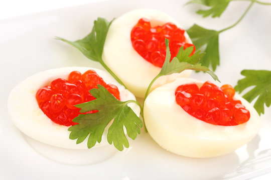 Red caviar in eggs on white plate close-up