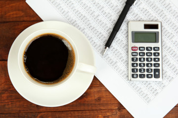 Cup of coffee on worktable covered with documents close up