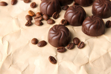 Chocolate candies and coffee beans, on beige paper background