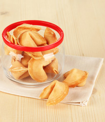Fortune cookies in glass jar, on wooden table