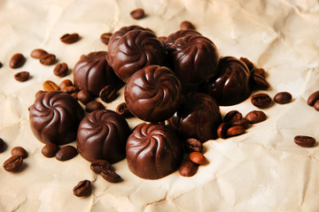Chocolate candies and coffee beans, on beige paper background