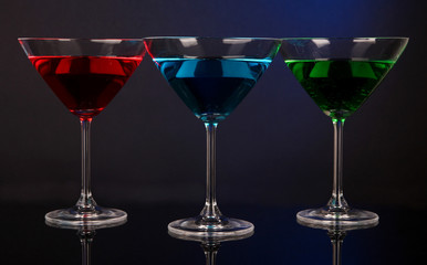 Alcoholic cocktails in martini glasses on dark blue background