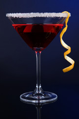Red cocktail in martini glass on dark blue background