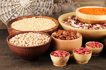Different kinds of beans in bowls on wooden background