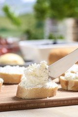 Preparing canapes with fresh cottage on wooden kitchen table