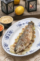 Fish plate in greek tavern. Roasted trout on onion.