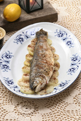 Fish plate in greek tavern. Roasted trout on onion.