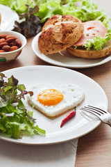 Fried egg on heart-shaped toast with salad for Valentine's Day