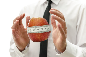 Male hand around apple wrapped with measuring tape