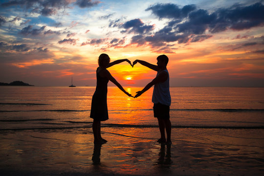 Couple holding hands heart-shape on the sea beach