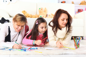 Beautiful girl draws with his mother and aunt.