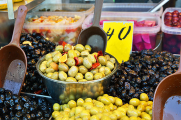 assortment of olives, pickles and salads in bowls on market stan