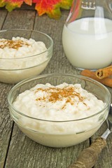 A bowl of milk rice with cinnamon on a wooden background