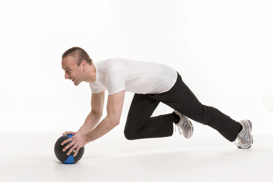Sportlicher junger Mann bei einer Gymnastikübung mit Medizinbal