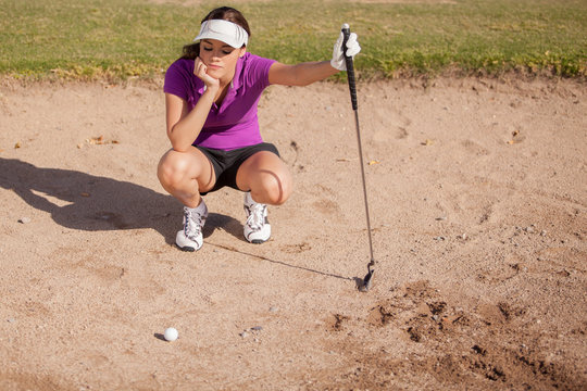 Young female golfer frustrated and stuck in a sand trap