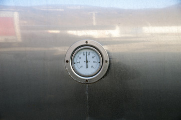 Close up of a gauge near a big holding tank