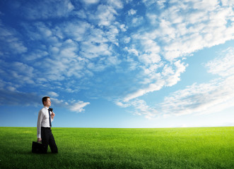 young business man wolking at the field of grass