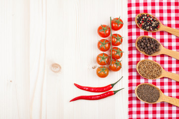 Wood background with tablecloth, chili, tomatoes, spices