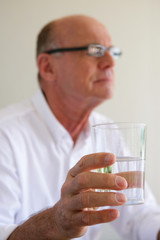 Elderly man taking medication with glass of water