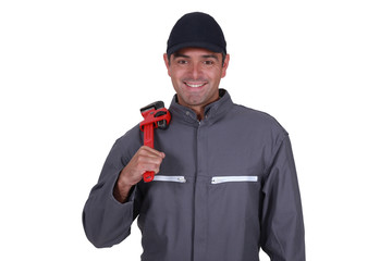 Cheerful plumber resting wrench on shoulder